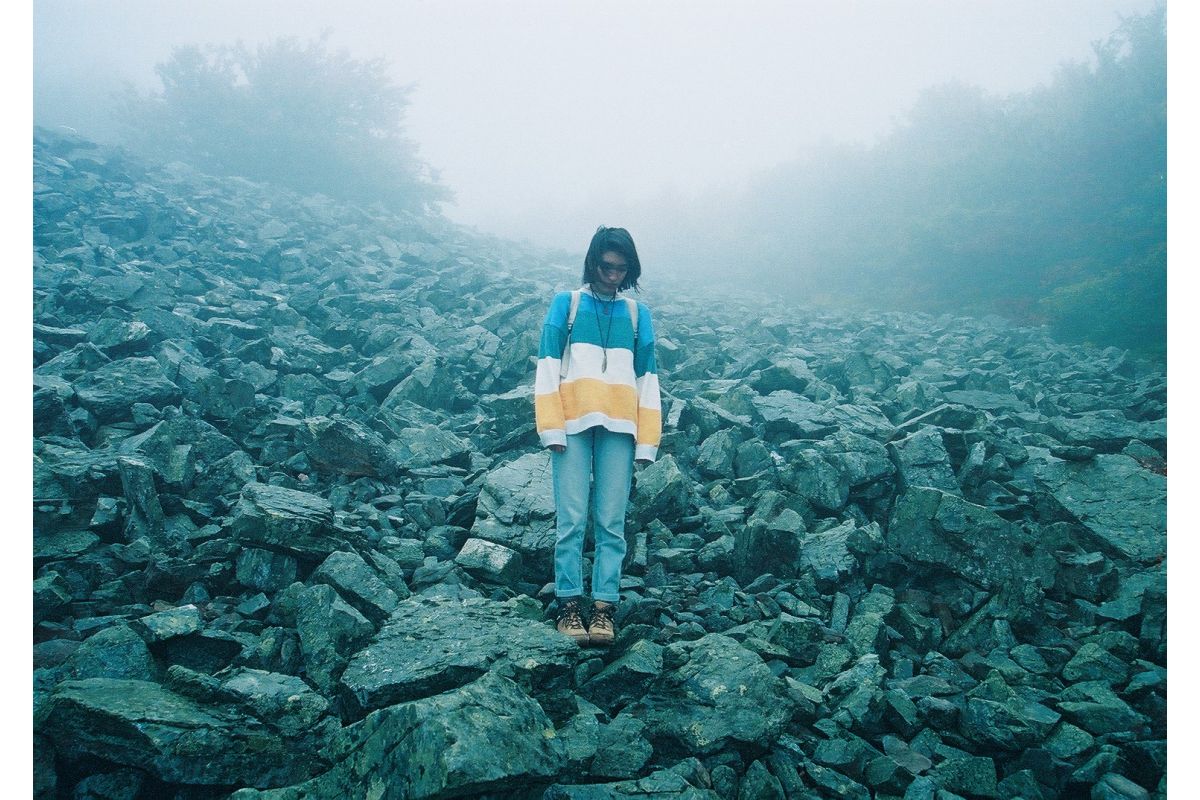 young woman standing on a hill of rocks taken on lomography colour negative 800 film